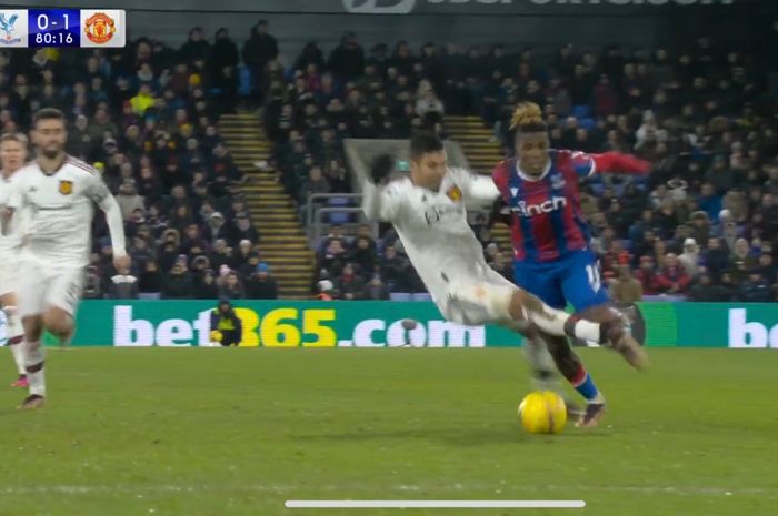 Gelandang Manchester United, Casemiro, melakukan pelanggaran ke Wilfried Zaha pada laga lanjutan Liga Inggris melawan Crystal Palace di Stadion Selhurst Park, Rabu (18/1/2023).