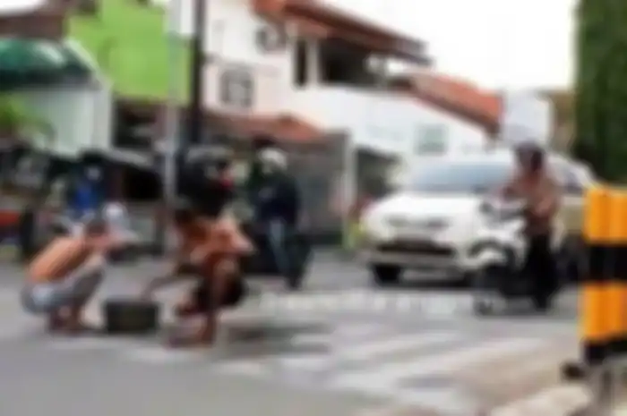Dua pemuda mandi di tengah jalan saat lampu merah di Kudus
