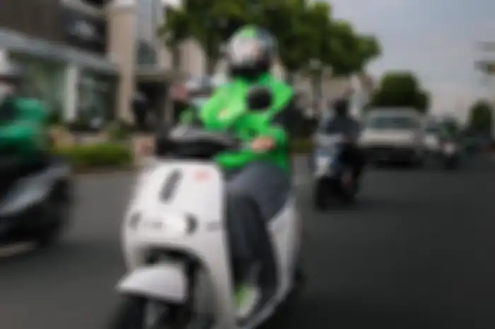 Foto ilustrasi driver ojol menaiki motor listrik.