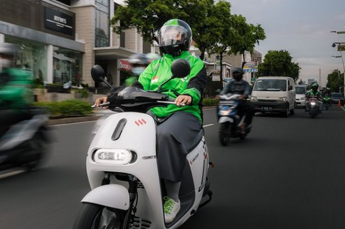 Foto ilustrasi driver ojol menaiki motor listrik.