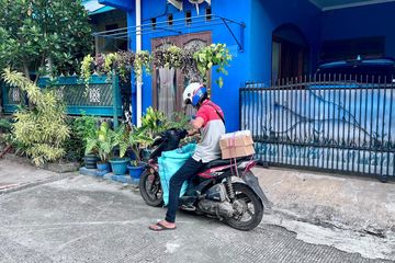 Seorang kurir sedang membawa tumpukan paket untuk ia antarkan ke area perumahan di Depok.