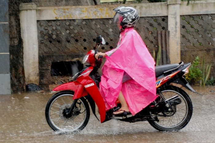 Ilustrasi pengendara motor hujan-hujanan.