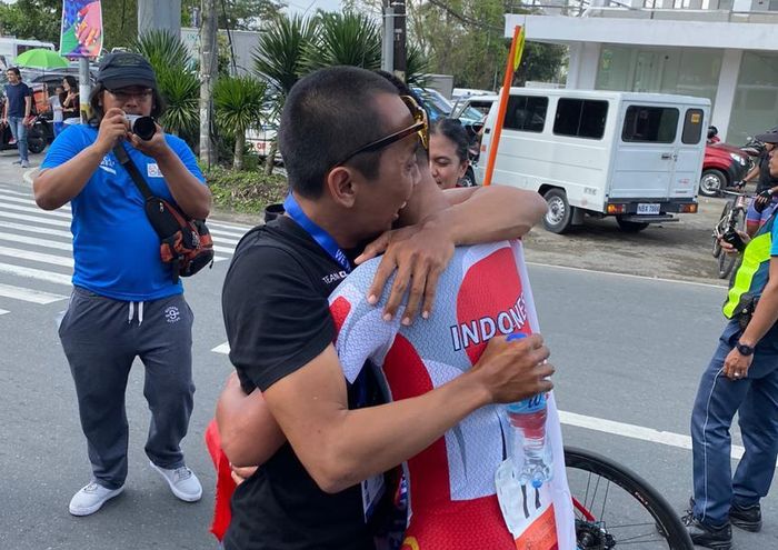 Pembalap sepeda putra Indonesia, Aiman Cahyadi, memeluk ofisial PB ISSI setelah memastikan diri meraih medali emas dari nomor individual time trial men elite pada SEA Games 2019.