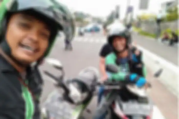 Dua driver ojol selfie di pinggir jalan.