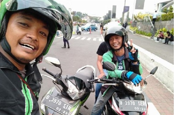 Dua driver ojol selfie di pinggir jalan.